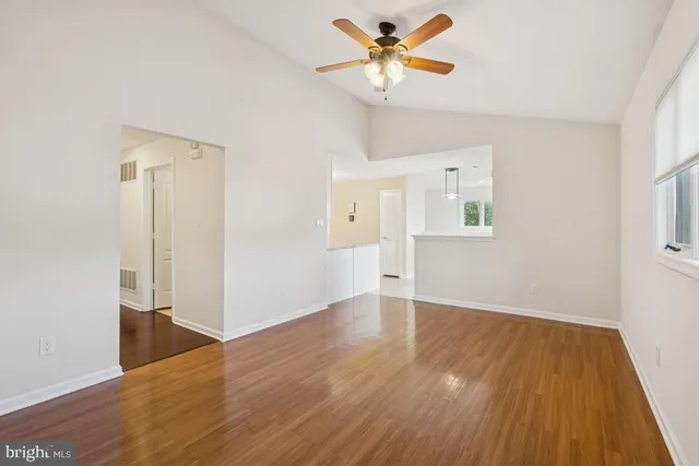 an empty room with wooden floor and a ceiling fan