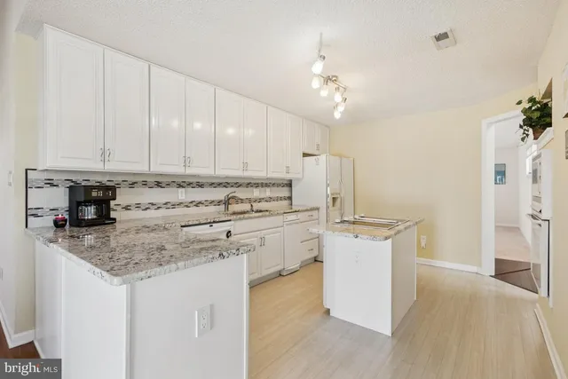 a kitchen with stainless steel appliances granite countertop a white cabinets and stove top oven