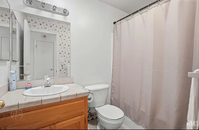 a bathroom with a sink a toilet and shower curtain