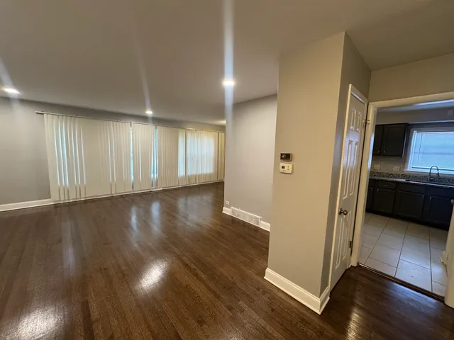 an empty room with wooden floor and a kitchen