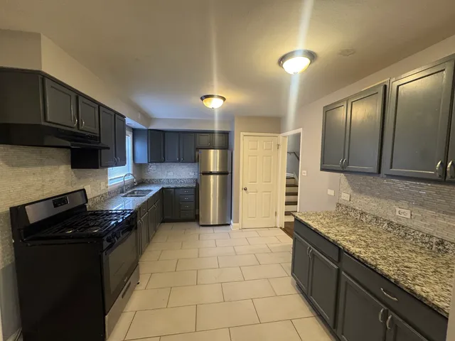 a kitchen with stainless steel appliances granite countertop a stove a sink and a refrigerator