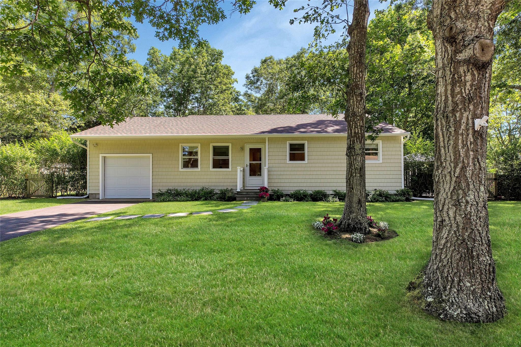 Ranch-style home featuring an attached garage, entry steps, concrete driveway, and a front lawn