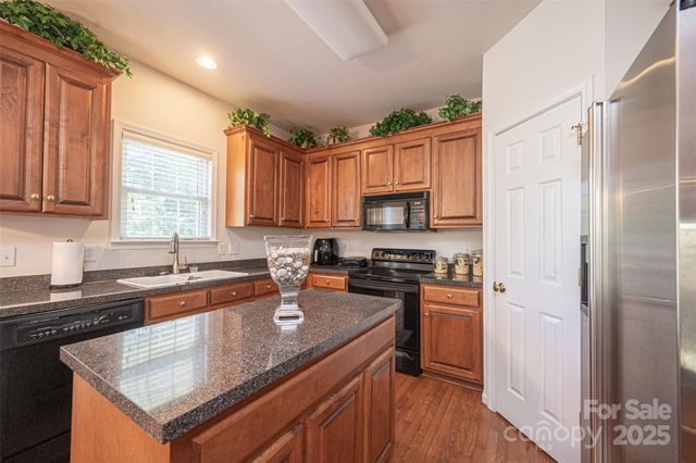 a kitchen with stainless steel appliances granite countertop a stove a sink dishwasher a refrigerator and a microwave oven with wooden floor