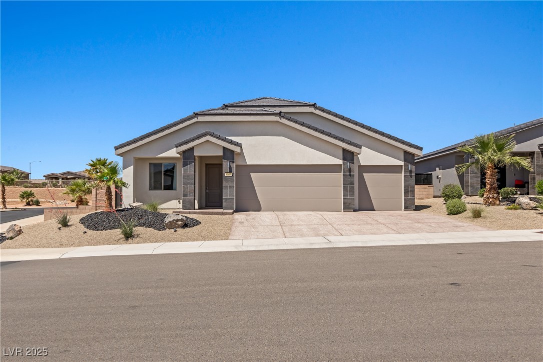 1357 Manassas Ridge Mesquite, NV 89027 - Photo 58 of 72 Ranch-style house featuring a garage, driveway, stucco siding, and stone siding
