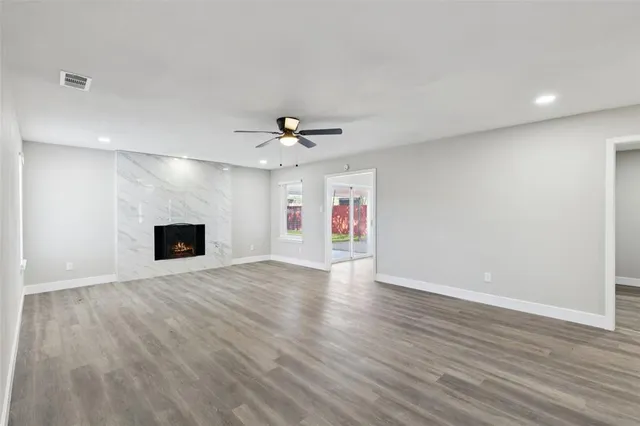 a view of an empty room with wooden floor and a fireplace