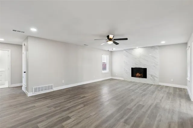 a view of an empty room with wooden floor and a ceiling fan