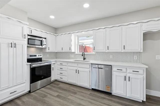 a kitchen with white cabinets white stainless steel appliances and sink