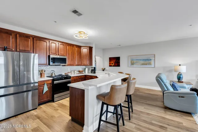 a kitchen with stainless steel appliances granite countertop a refrigerator a stove a sink dishwasher and a refrigerator with wooden floor