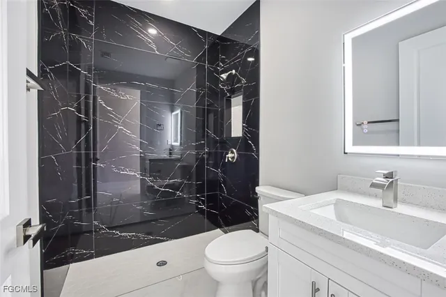a bathroom with a granite countertop sink a toilet and shower