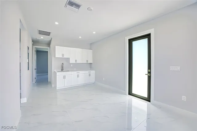 a view of kitchen with refrigerator and white cabinets