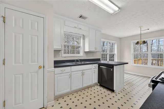 a kitchen with granite countertop white cabinets and window