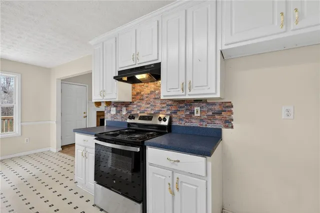 a kitchen with granite countertop a sink a stove and cabinets