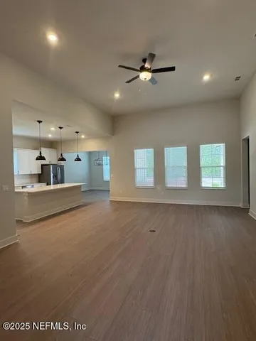 a view of an empty room with window and wooden floor