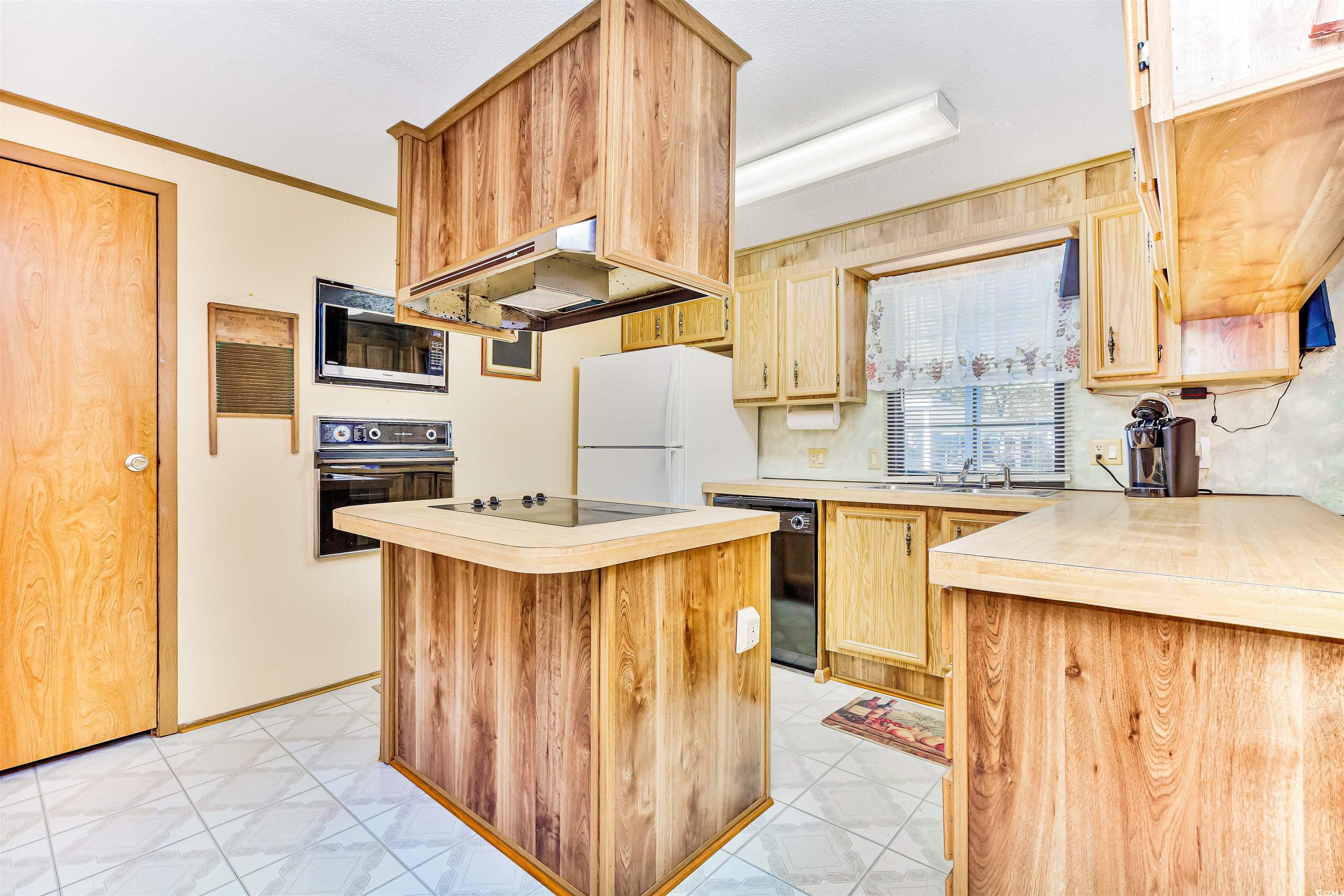 494 Clubhouse Road Murrells Inlet, SC 29576 - Photo 17 of 26 Kitchen with black appliances, light countertops, a kitchen island, under cabinet range hood, and ornamental molding