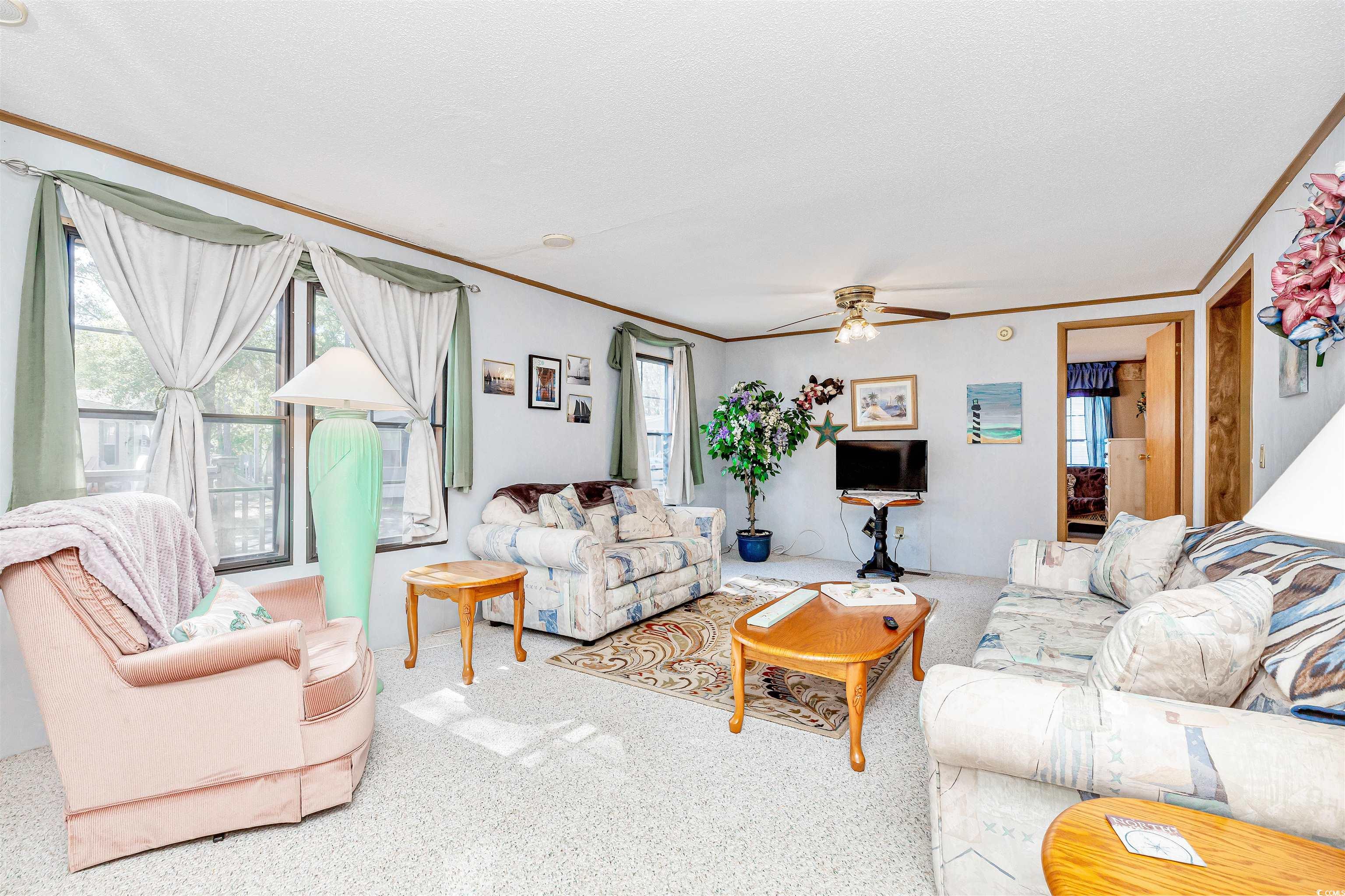 494 Clubhouse Road Murrells Inlet, SC 29576 - Photo 9 of 26 Carpeted living area with healthy amount of natural light, ornamental molding, and a ceiling fan