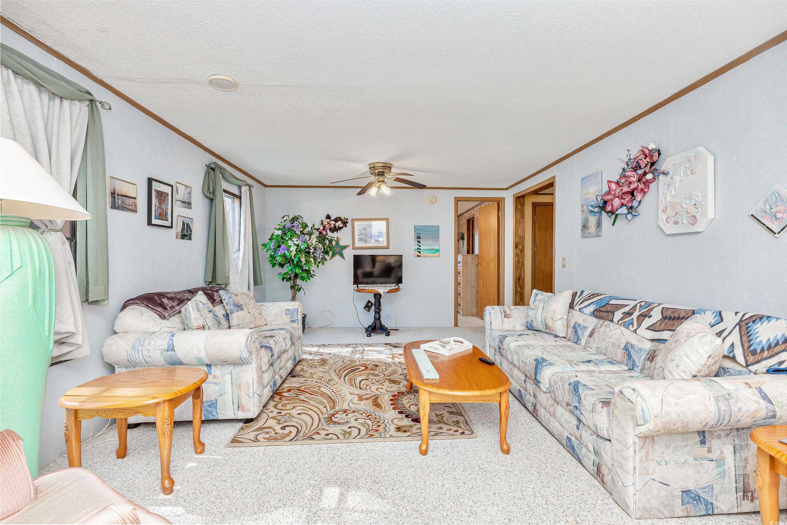494 Clubhouse Road Murrells Inlet, SC 29576 - Photo 10 of 26 Carpeted living room featuring crown molding, a ceiling fan, and a textured ceiling