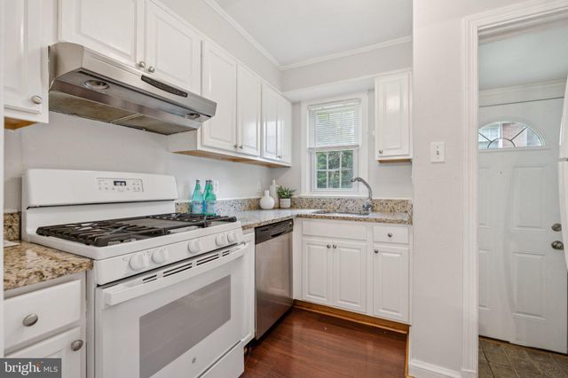 a kitchen with granite countertop cabinets stainless steel appliances and wooden floor