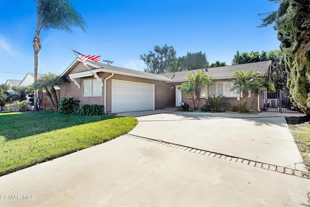 a front view of a house with a yard and potted plants