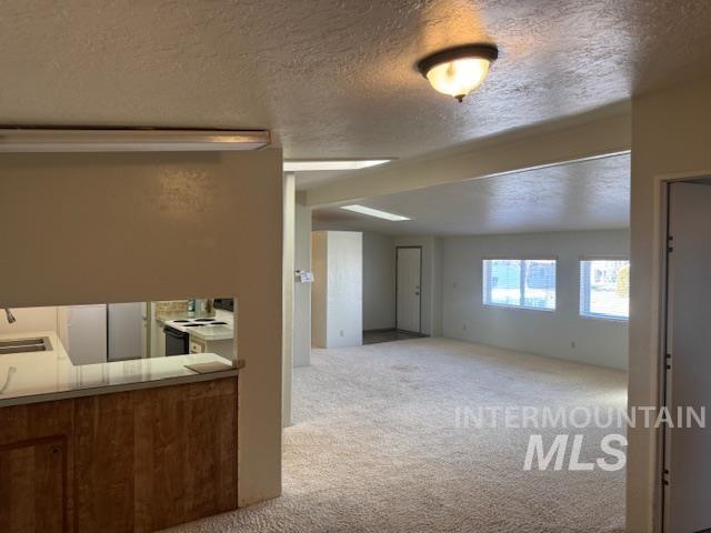910 Moonglo, Unit 49 Buhl, ID 83316 - Photo 16 of 16 Kitchen featuring light carpet, white range with electric stovetop, a textured ceiling, light countertops, and open floor plan