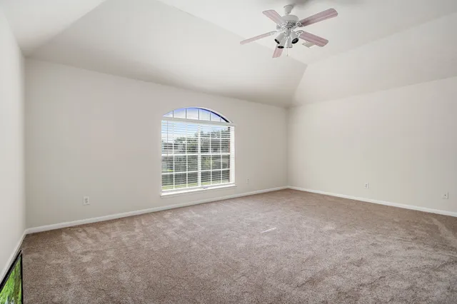 an empty room with windows and ceiling fan view