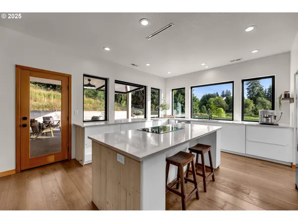 a kitchen with stainless steel appliances granite countertop a kitchen island a stove and a large window