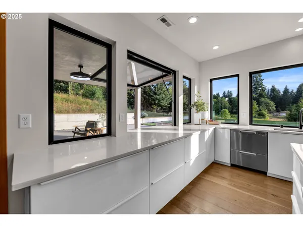 a large white kitchen with sink and large window