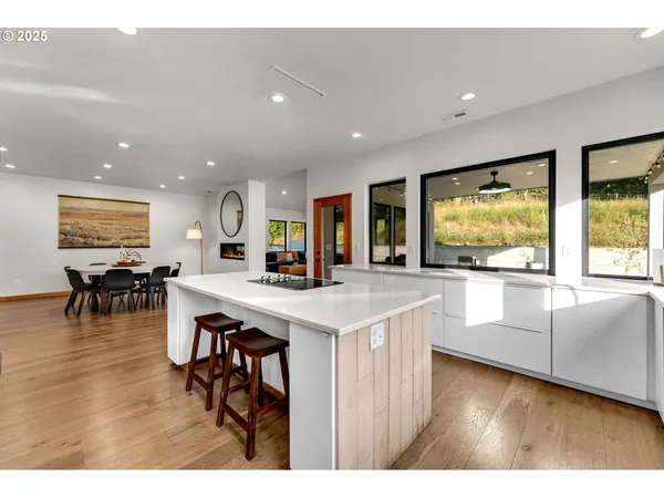 a open kitchen with stainless steel appliances granite countertop a refrigerator a stove a dining table and chairs with wooden floor