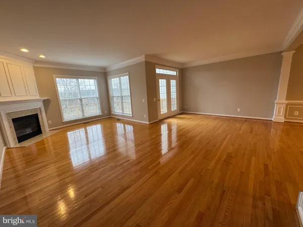 a view of an empty room with wooden floor and windows