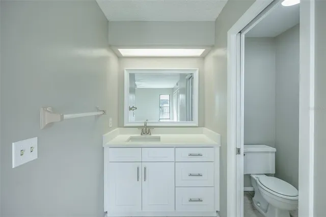 a bathroom with a granite countertop sink toilet and mirror
