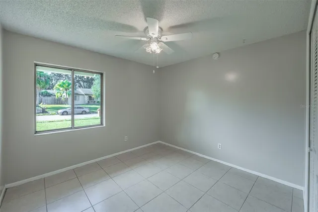 an empty room with a chandelier fan and windows