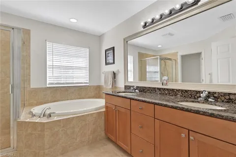 a bathroom with a granite countertop tub sink and mirror