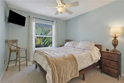 a bedroom with a bed a flat screen tv and a chandelier