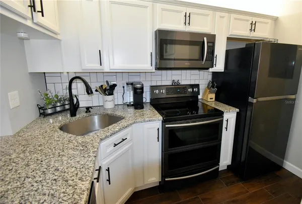 a kitchen with granite countertop a refrigerator stove and microwave