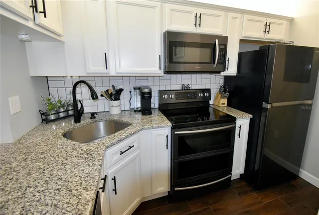 a kitchen with granite countertop a refrigerator stove and microwave