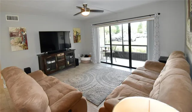 a living room with furniture a flat screen tv and a floor to ceiling window