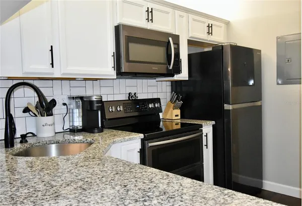 a kitchen with stainless steel appliances kitchen island granite countertop a refrigerator stove and sink