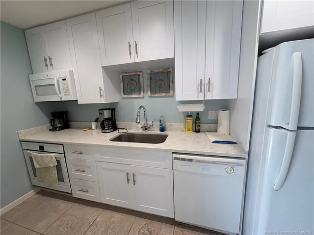 a kitchen with stainless steel appliances granite countertop a sink a refrigerator a stove and white cabinets