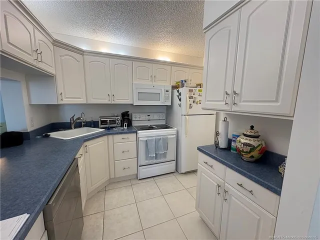 a kitchen with granite countertop white cabinets and stainless steel appliances