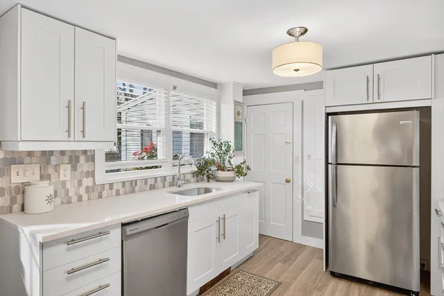 a kitchen with white cabinets and refrigerator