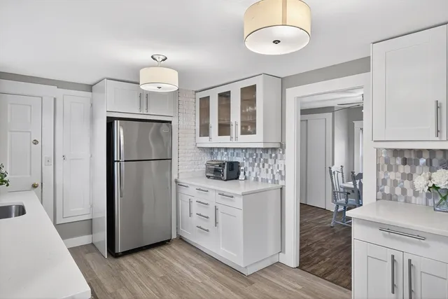 a kitchen with stainless steel appliances granite countertop a refrigerator a stove a sink and white cabinets with wooden floor