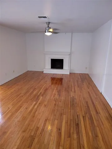 a view of empty room with wooden floor and fireplace