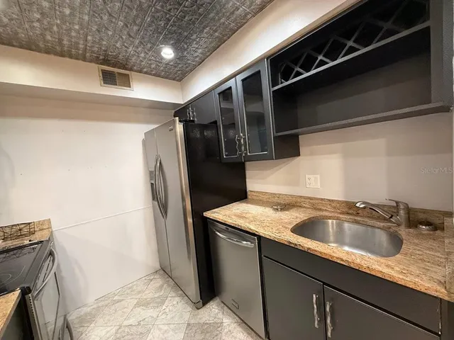 a kitchen with stainless steel appliances granite countertop a sink and a refrigerator
