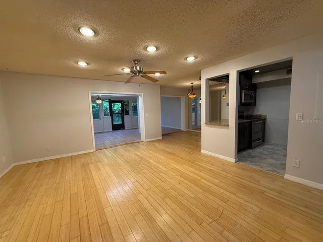 an empty room with wooden floor and entrance to other room