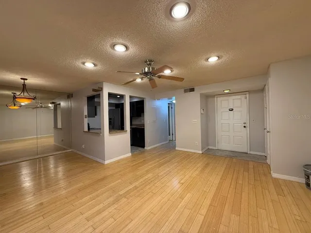 a view of an empty room with kitchen and a window