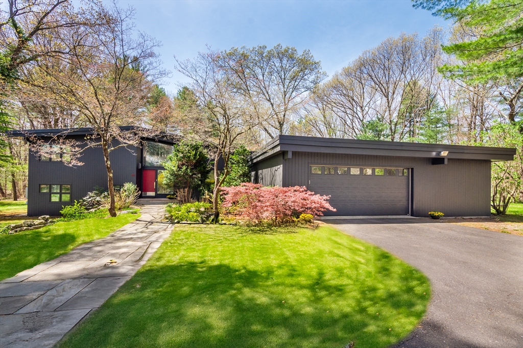 a front view of house with yard and trees in the background