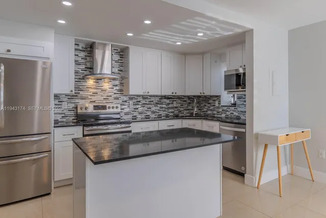 a kitchen with kitchen island a sink stainless steel appliances and cabinets