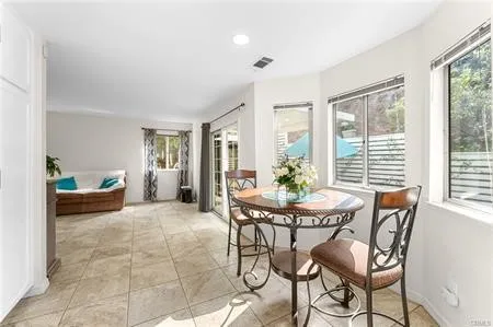 a kitchen with stainless steel appliances kitchen island granite countertop a refrigerator a stove a dining table and chairs with wooden floor