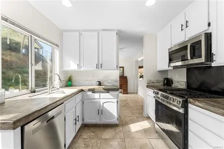 a kitchen with stainless steel appliances granite countertop a stove top oven a sink a dining table and chairs with wooden floor