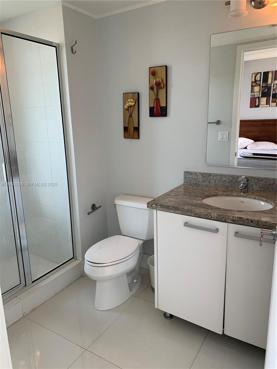 185 Southwest 7th Street, Unit 2202 Miami, FL 33130 - Photo 16 of 36 a bathroom with a granite countertop toilet sink and a mirror