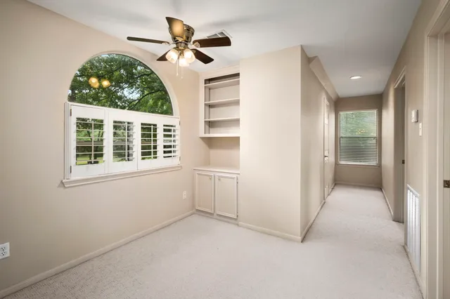 an empty room with windows and ceiling fan